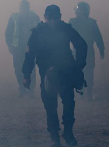 Mexico's Federal Police officers are seen through the smoke of tear g