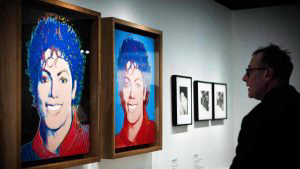 A man looks at artworks by Andy Warhol depicting Michael Jackson