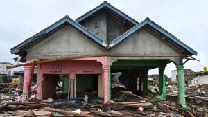 TOPSHOT - A damaged house stands amid tsunami debris at the Sumber Ja