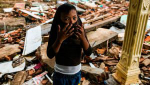 TOPSHOT - A boy covers his face as he stands outside a collapsed hous