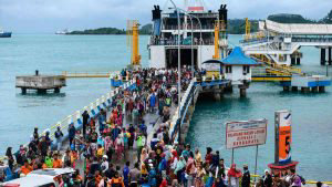 Residents disembark from a ferry at the port after being evacuated fr