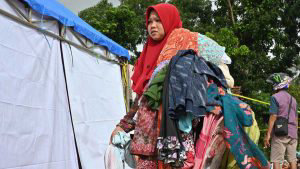 TOPSHOT - A woman carries clothes donated by people at a help centre