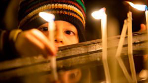 A child lights a candle during Christmas Mass at Saint Antuan Church