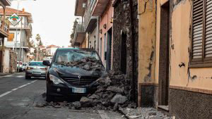 A collapsed wall and a damaged car are pictured in Zafferana Etnea ne