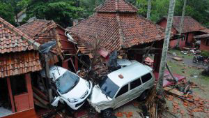 Damaged buildings and cars are seen in Anyer