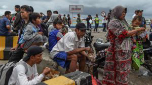 Residents eat after disembarking from a ferry at the port after being