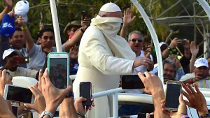 Pope Francis' cape sweeps in his face as he arrives for his welcome c