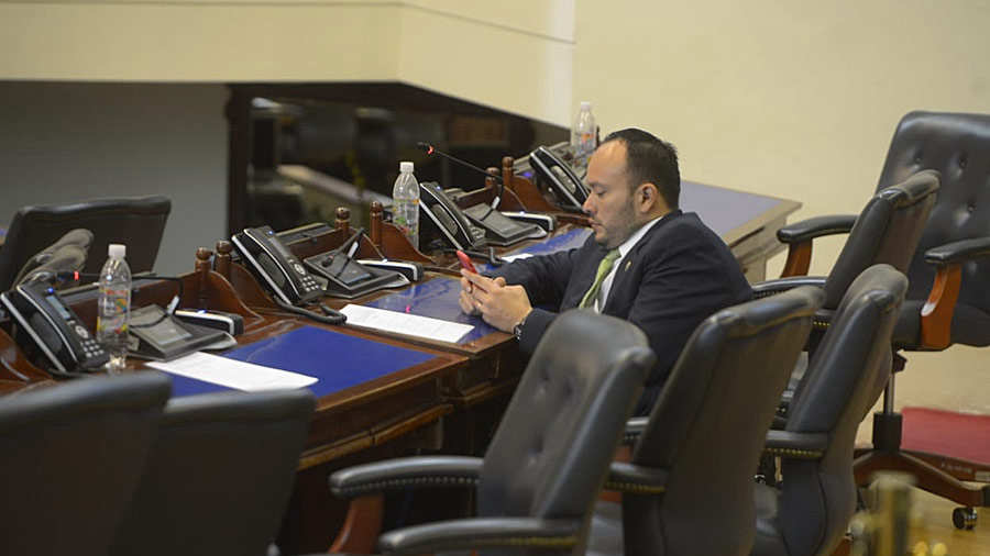 El diputado David Reyes, de ARENA, revisa su teléfono luego de concluir la plenaria que duró alrededor de quince minutos.
Foto EDH/ Josué Parada
