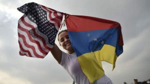 A woman holds the Venezuelan and US flags as she waits for the start