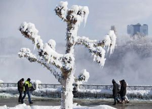 People walk by trees covered in ice from the mist of the falls in Nia