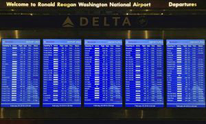 A board showing many flights as snow falls at Ronald Reagan Washingto