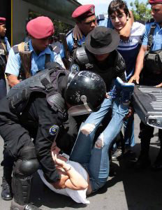 Nicaraguan riot police officers arrest protesters before a demonstrat