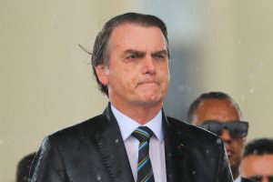 Brazilian President Jair Bolsonaro is drenched with rain during a dow