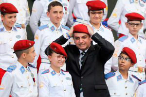 Brazilian President Jair Bolsonaro puts a beret on as he poses with s