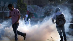 Venezuelans run away from tear gas during scuffles with security forc