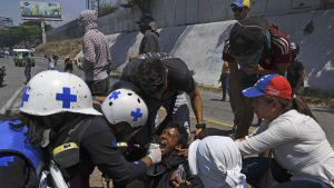 An opposition demonstrator affected by tear gas is assisted during cl