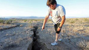 A man looks into a fissure that opened in the desert during a powerful earthquake that struck Southern California, near the city of Ridgecrest