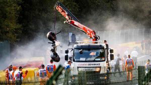 Track marshals look on as a crane lift parts of the damaged car of Sa
