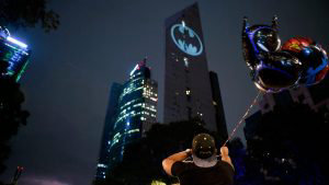 A fan man looks at Batman's symbol projected over the Reforma Tower o