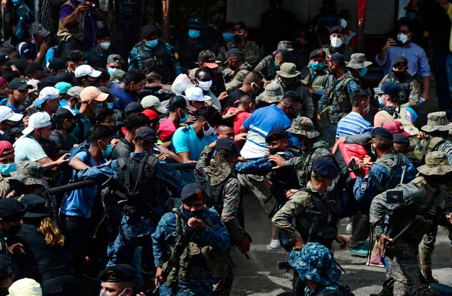 Honduran migrants break the police fence to enter Guatemala on their