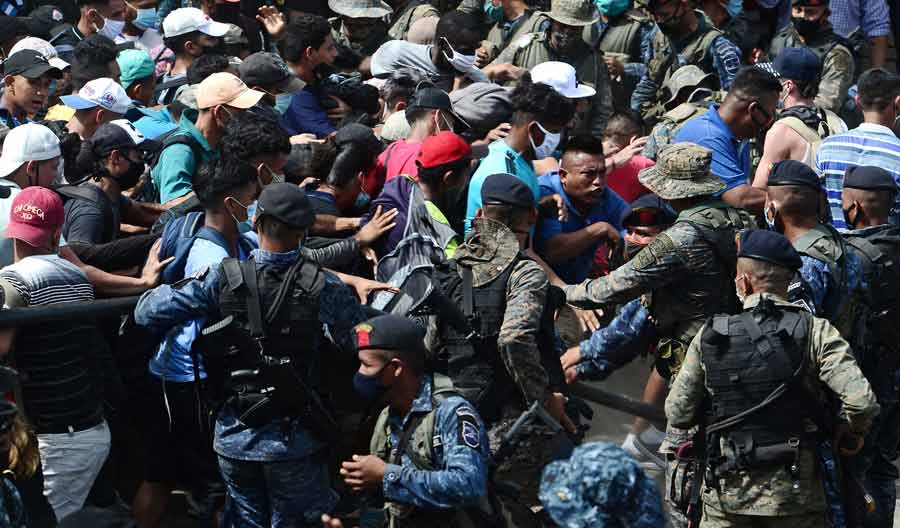 Honduran migrants break the police fence to enter Guatemala on their