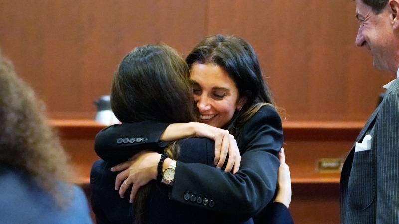 Joelle Rich abraza a Camille Vasquez, de espaldas a la cámara, mientras el abogado Ben Chew (R) observa, en el juzgado del condado de Fairfax, Virginia, el 16 de mayo de 2022, cuando Depp ganó el juicio contra Amber Heard. Foto: archivo/AFP
