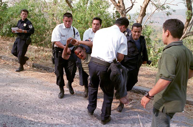 Agentes de la policía cargan a un de dos asaltantes heridos durante un tiroteo en marzo de 2000. Foto Antolín Escobar