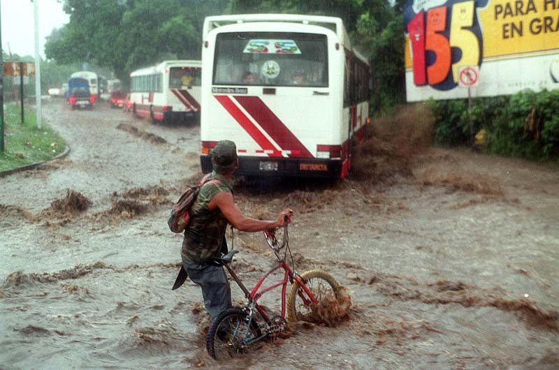 Un hombre en bicicleta cruza una calle inundada en Santa Ana durante una tormenta en septiembre de 1999. Foto Antolín Escobar