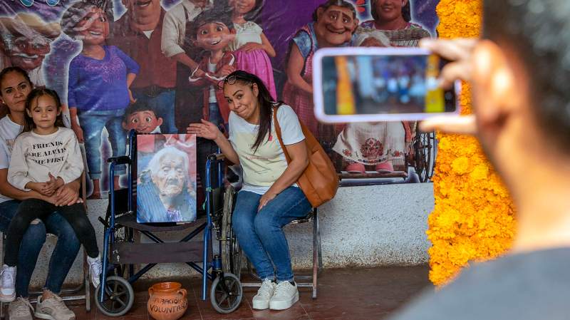 Los turistas posan para una foto en la casa de María Salud Ramírez Caballero, conocida como Mama Coco, en Santa Fe de la Laguna. Foto: ENRIQUE CASTRO / AFP 