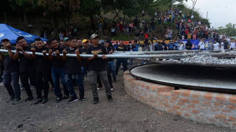 El grupo de hombres responsables de tapar la enorme pupusa con una tapadera con carbón que facilita su cocción. Foto: EDH / Jorge Reyes