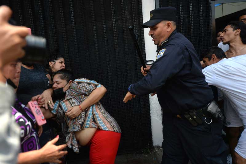 Un policía empuja violentamente a una mujer que intentaba abrazar y besar a un joven detenido que era llevado a prisión desde las bartolinas de la PNC de San Salvador. FOTO EDH JONATAN FUNES