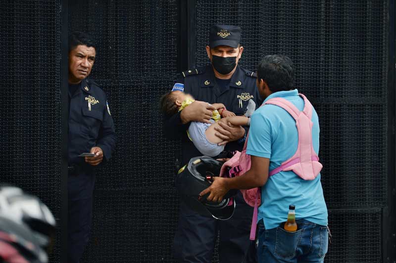 Un hombre con su hija suplica a policías, en la entrada de las bartolinas de la PNC, que dejaran que la madre detenida de la niña la amamantara por un momento. Los policías se compadecieron y entraron con la bebé. Luego la devolvieron al padre. FOTO EDH JONATAN FUNES