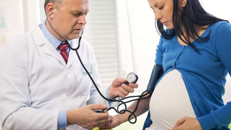 Médico toma la presión a joven madre. Foto/Shutterstock