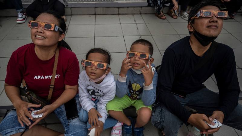Familia se protege con gafas especiales durante el eclipse de abril 2023 en Indonesia