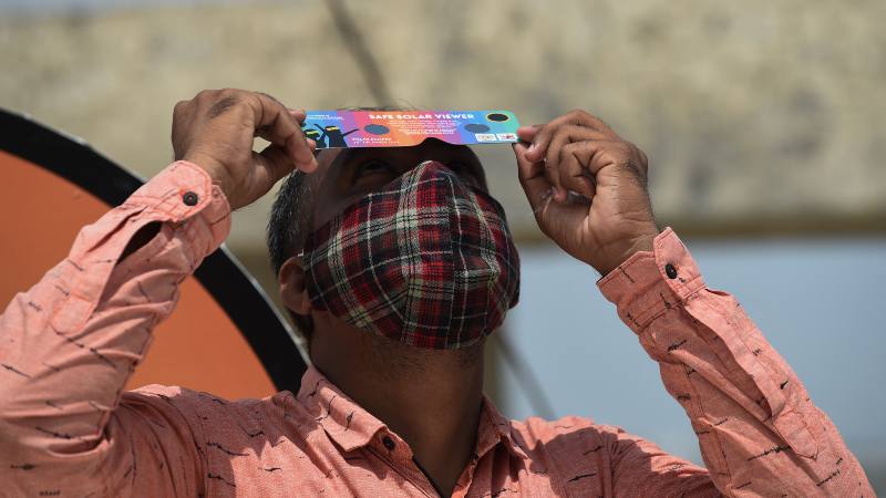 Hombre admira eclipse de sol con lentes especiales en la India en 2020