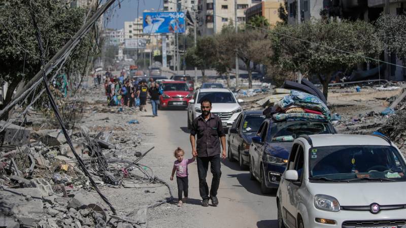 hombre camina con un niño en ciudad destruida de Gaza