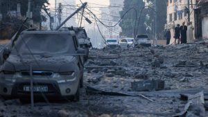 La gente camina junto a las ruinas en una calle afectada por los ataques aéreos israelíes en la ciudad de Gaza