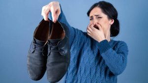 Mujer reacciona ante el mal olor de un par de zapatos sucios