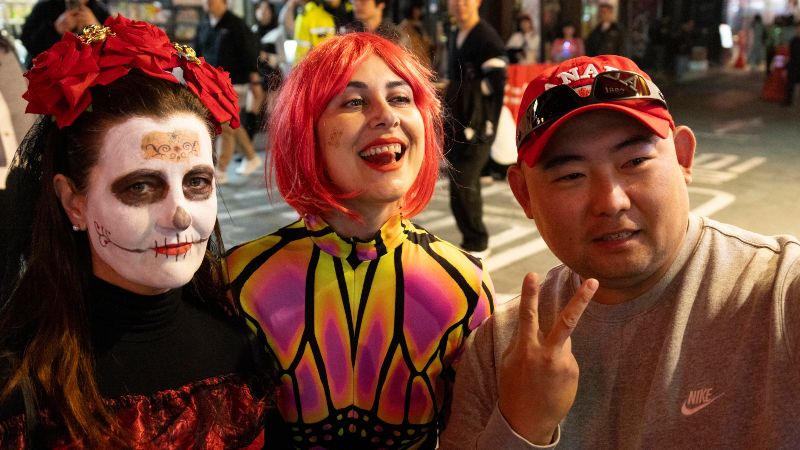 un hombre toma un selfie con personas vestidas con disfraces durante las festividades de Halloween en la calle Itaewon en Seúl.