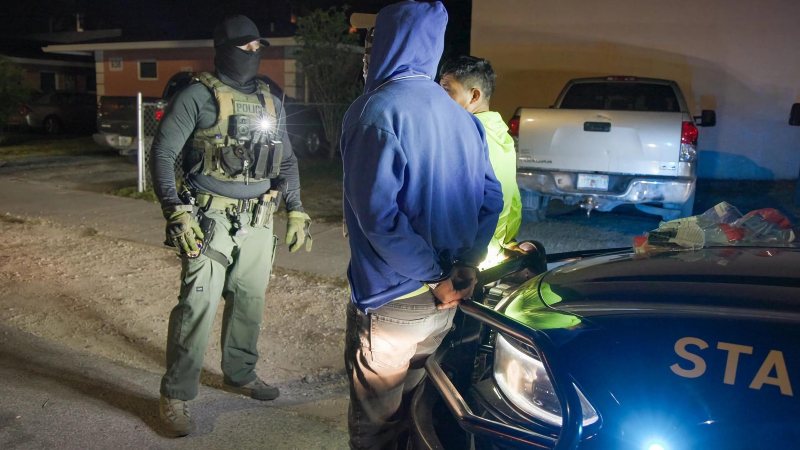 Fotografía cedida por el Servicio de Control de Inmigración (ICE) donde aparece un agente de la policía durante el arresto de dos indocumentados en Florida (Estados Unidos). Foto / EFE