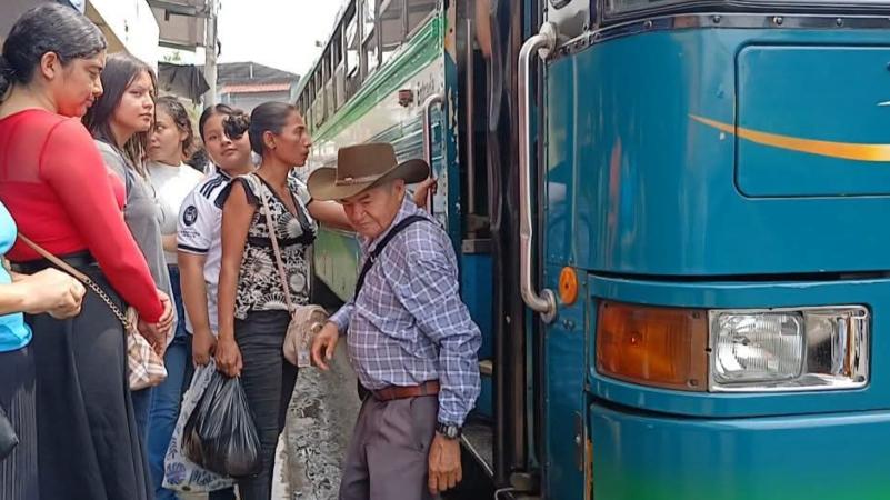 Pasajeros subiendo y otros bajando en un bus que recorre de Gotera a Perquin. / 