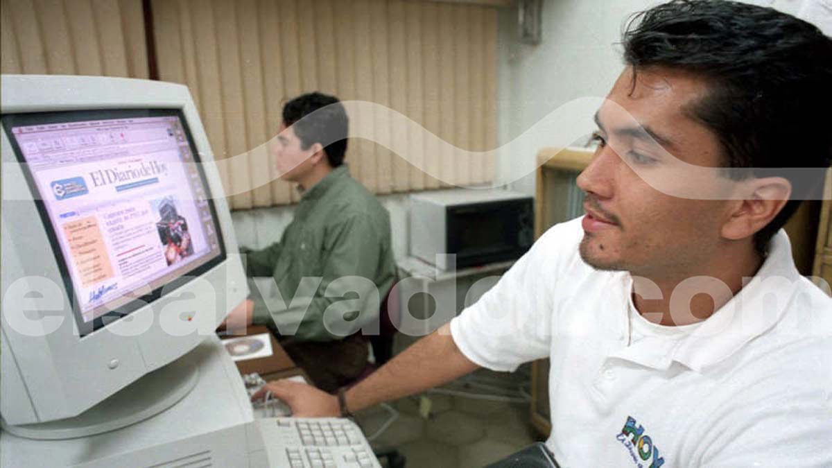 Joven profesional salvadoreño utilizando una computadora Macintosh de pantalla blanca antigua para navegar en la página web de elsalvador.com a finales de los años 90.