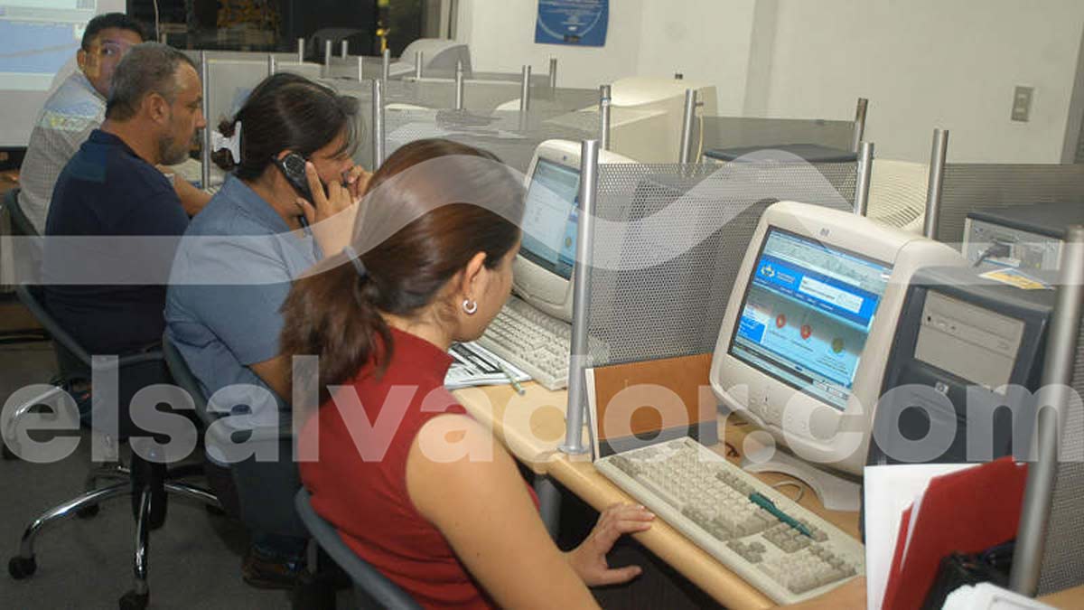 Mujeres trabajando frente a computadoras de escritorio blancas en una sala de navegación en El Salvador.