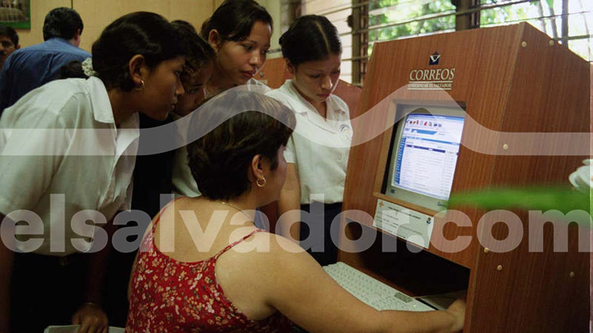 Estudiantes salvadoreñas en uniforme reunidas alrededor de una cabina de internet de Correos de El Salvador usando un navegador web.