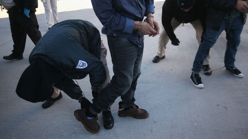 MESA, AZ - FEBRUARY 28: A security contractor hired by U.S. Immigration and Customs Enforcement (ICE), frisks a Honduran immigration detainee before a deportation flight to San Pedro Sula, Honduras on February 28, 2013 in Mesa, Arizona. ICE operates 4-5 flights per week from Mesa to Central America, deporting hundreds of undocumented immigrants detained in western states of the U.S. With the possibility of federal budget sequestration, ICE released 303 immigration detainees in the last week from detention centers throughout Arizona. More than 2,000 immigration detainees remain in ICE custody in the state. Most of them will be scheduled for deportation within weeks, while others remain for longer periods while their immigration cases work through the courts.   John Moore/Getty Images/AFP (Photo by JOHN MOORE / GETTY IMAGES NORTH AMERICA / Getty Images via AFP)