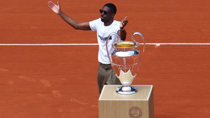 El delantero francés del Paris Saint-Germain, Ousmane Dembélé, lleva el trofeo de la UEFA Champions League a la cancha Philippe-Chatrier como parte del torneo de tenis Abierto de Francia, el día 9 en el Complejo Roland-Garros en París el 2 de junio de 2025. Foto: AFP