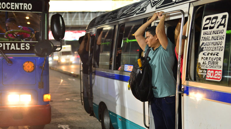 Un pasajero cuelga de un microbus de la ruta 29 en la parada de buses en Plaza Mundo, Soyapango. Foto EDH / Emerson Del Cid