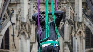 Una grúa eleva una estatua de Santo Tomás, la última de las 16 estatuas gigantes de apóstoles revestidas de cobre en colocarse.