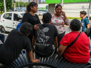 Al centro, un menor guatemalteco tras ser deportado desde EE. UU., en una base aérea militar guatemalteca. Familiares hablan con él tras recibirlo. En el caso del menor, sí ocurrió la deportación. / AFP