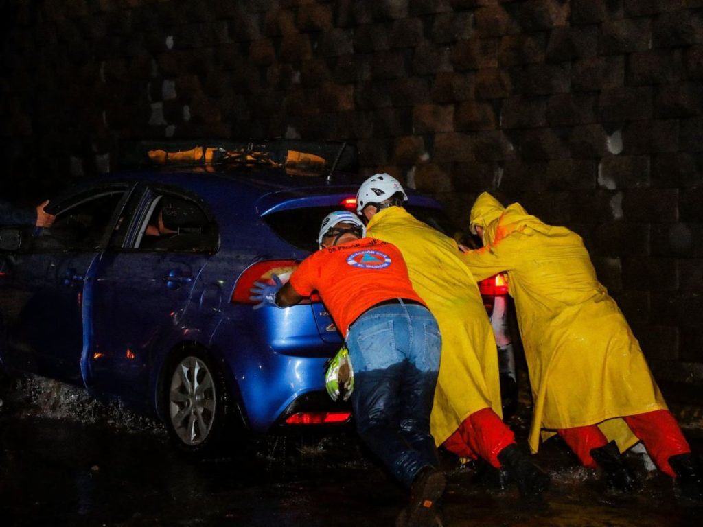 Elementos de Protección Civil ayudan a e un vehículo salir de las inundaciones